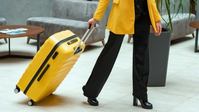 Person in Yellow Coat Pulling a Suitcase