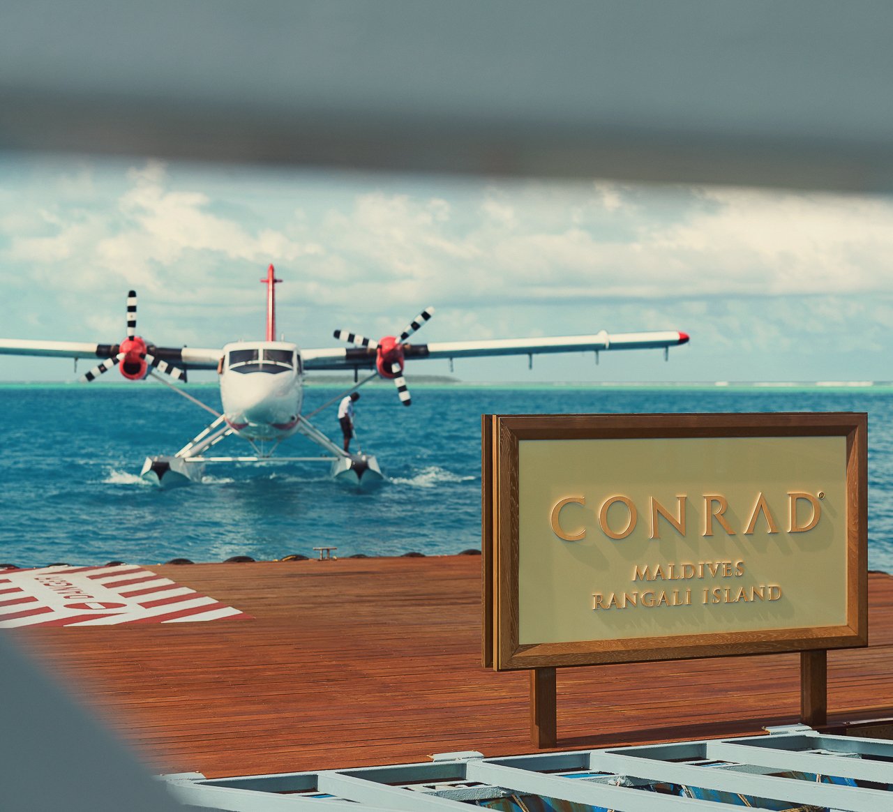 A seaplane at the Conrad Maldives Rangali Island arrival platform over the turquoise water.