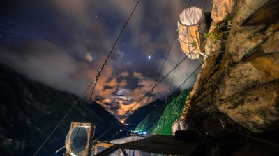 The Skylodge capsules illuminated at night against a backdrop of stars, creating a magical and surreal experience high above the valley.