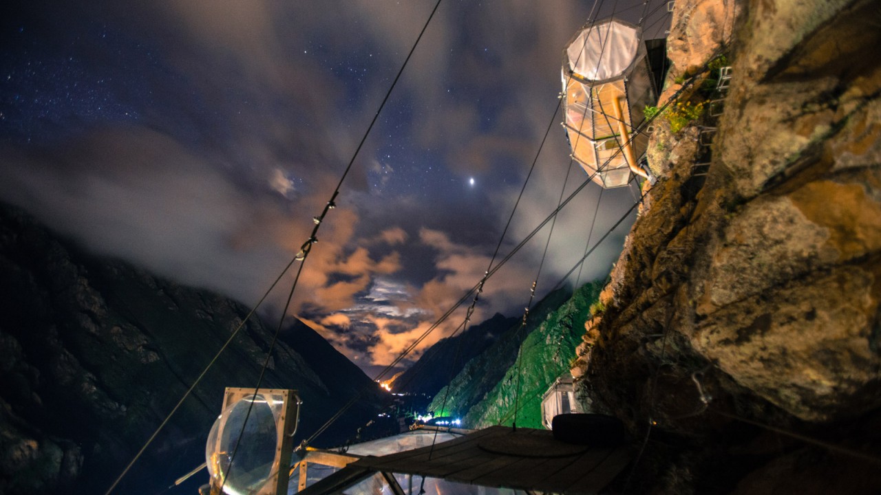 The Skylodge capsules illuminated at night against a backdrop of stars, creating a magical and surreal experience high above the valley.