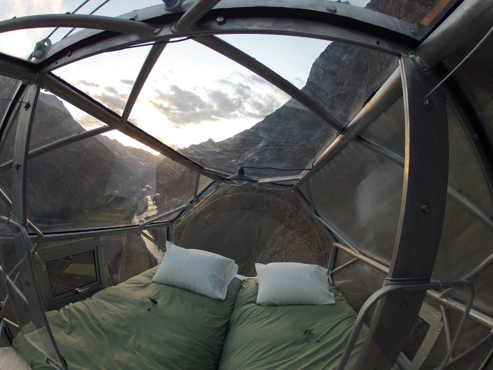 Inside the Skylodge capsule, showing comfortable beds and the stunning 300-degree panoramic view of the Sacred Valley through the transparent walls.