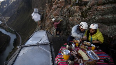 Guests enjoying a gourmet meal on an open-air platform attached to the Skylodge, surrounded by majestic mountain views.