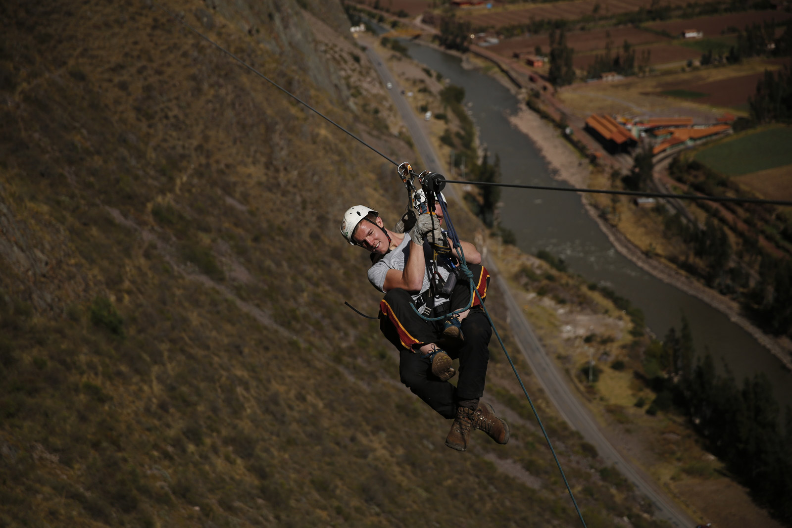 A person ziplining down from Skylodge Adventure Suites, soaring above the Sacred Valley with no need for manual braking on the long cable.