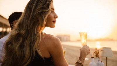 A guest enjoys a tranquil moment with a drink while taking in the serene beachfront views.