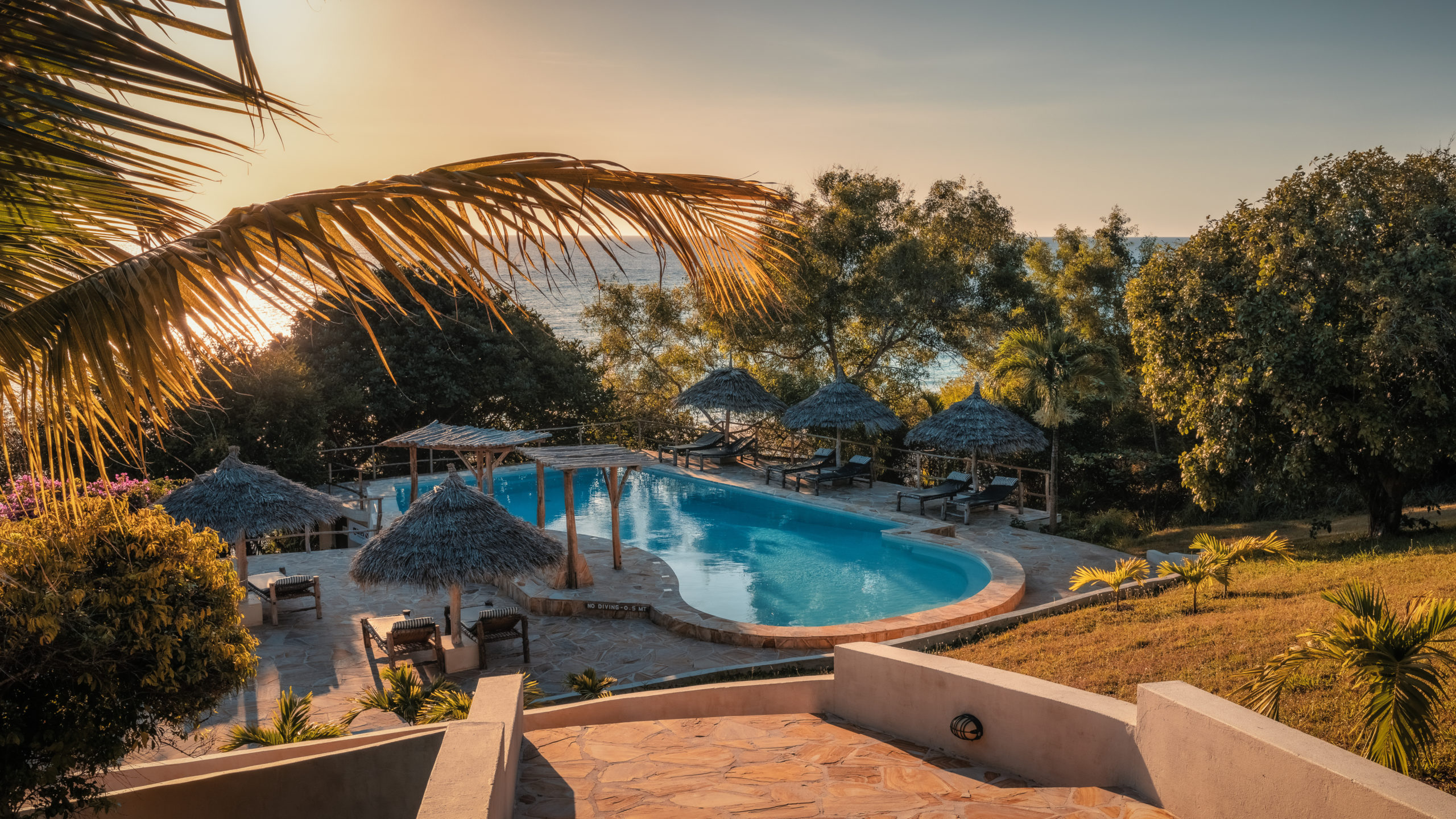 The infinity pool at The Manta Resort overlooking the sparkling turquoise ocean and white sand beach of Pemba Island.