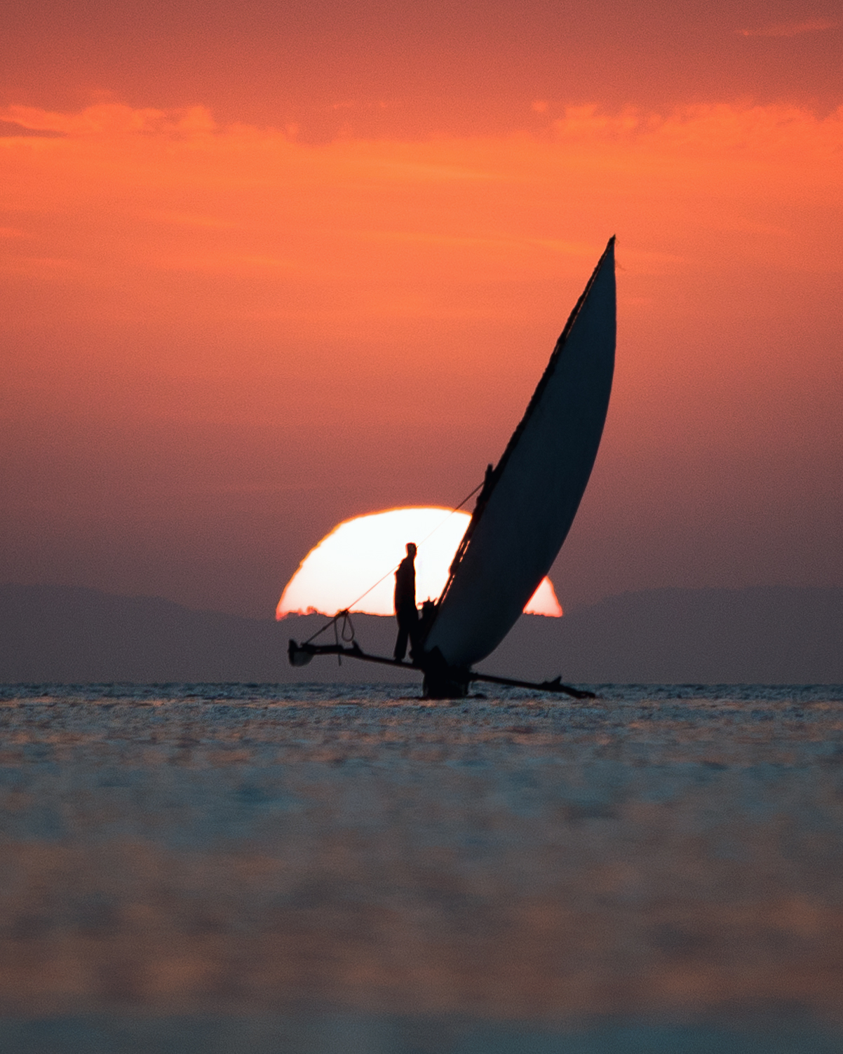 Traditional Ngalawa sailing canoe at sunset, used for The Manta Resort's iconic sunset cruises in Pemba.