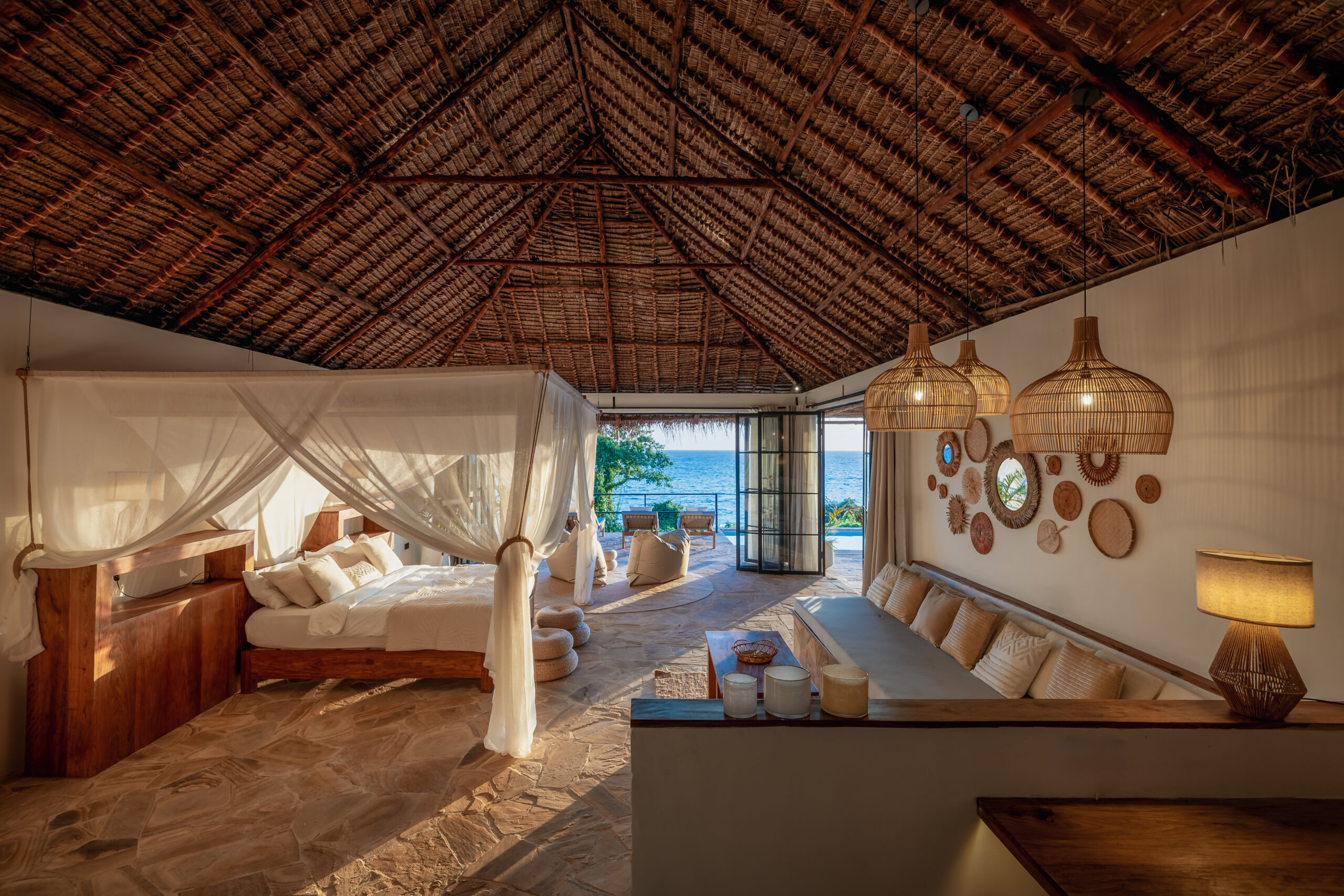 Sunset view from the bedroom of an Oceanview Villa at The Manta Resort, featuring a king bed and direct access to a private deck.