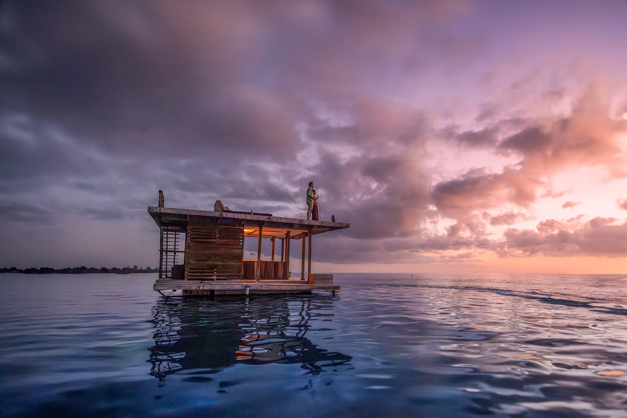 A couple enjoying sunset on the top deck of The Underwater Room at The Manta Resort, a floating suite in the Pemba Channel.