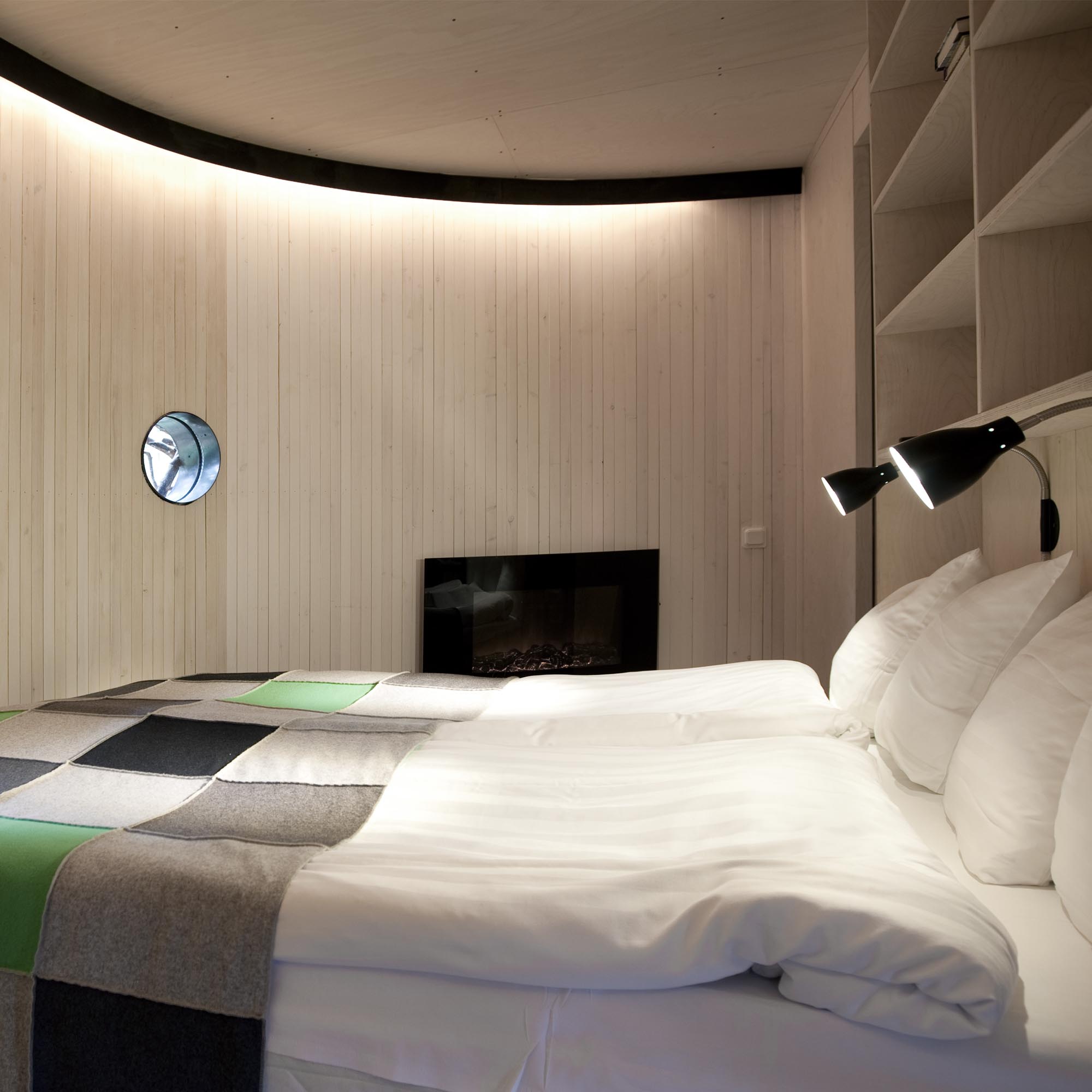 Cozy wooden interior of The Bird's Nest room at Treehotel, featuring a double bed and single beds for families.