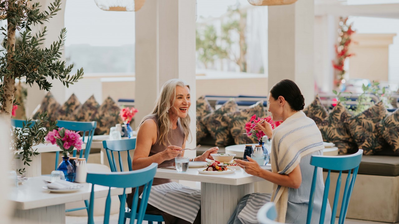 Diners enjoying a meal in the lush, greenery-filled setting of OIA restaurant.