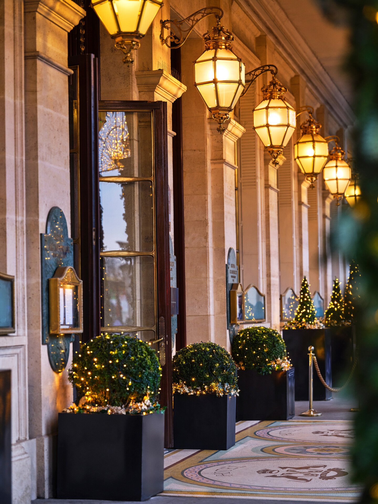 A festive nighttime view of Le Meurice's exterior on a decorated Rue de Rivoli, with the Tuileries Garden nearby.