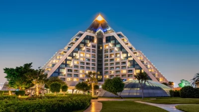 The iconic pyramid structure of Raffles Dubai during a beautiful sunset.