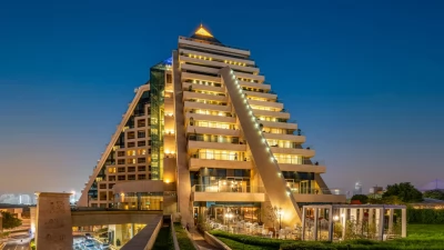 The stunning pyramid architecture of Raffles Dubai during a beautiful sunset.