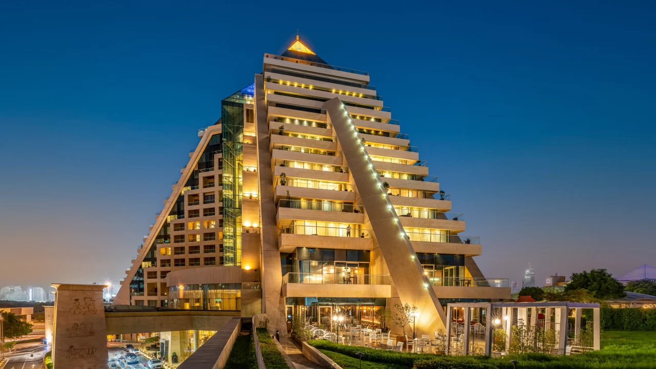 The stunning pyramid architecture of Raffles Dubai during a beautiful sunset.