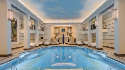 The stunning mosaic-tiled swimming pool at the Ritz Club & Spa, under a painted sky.