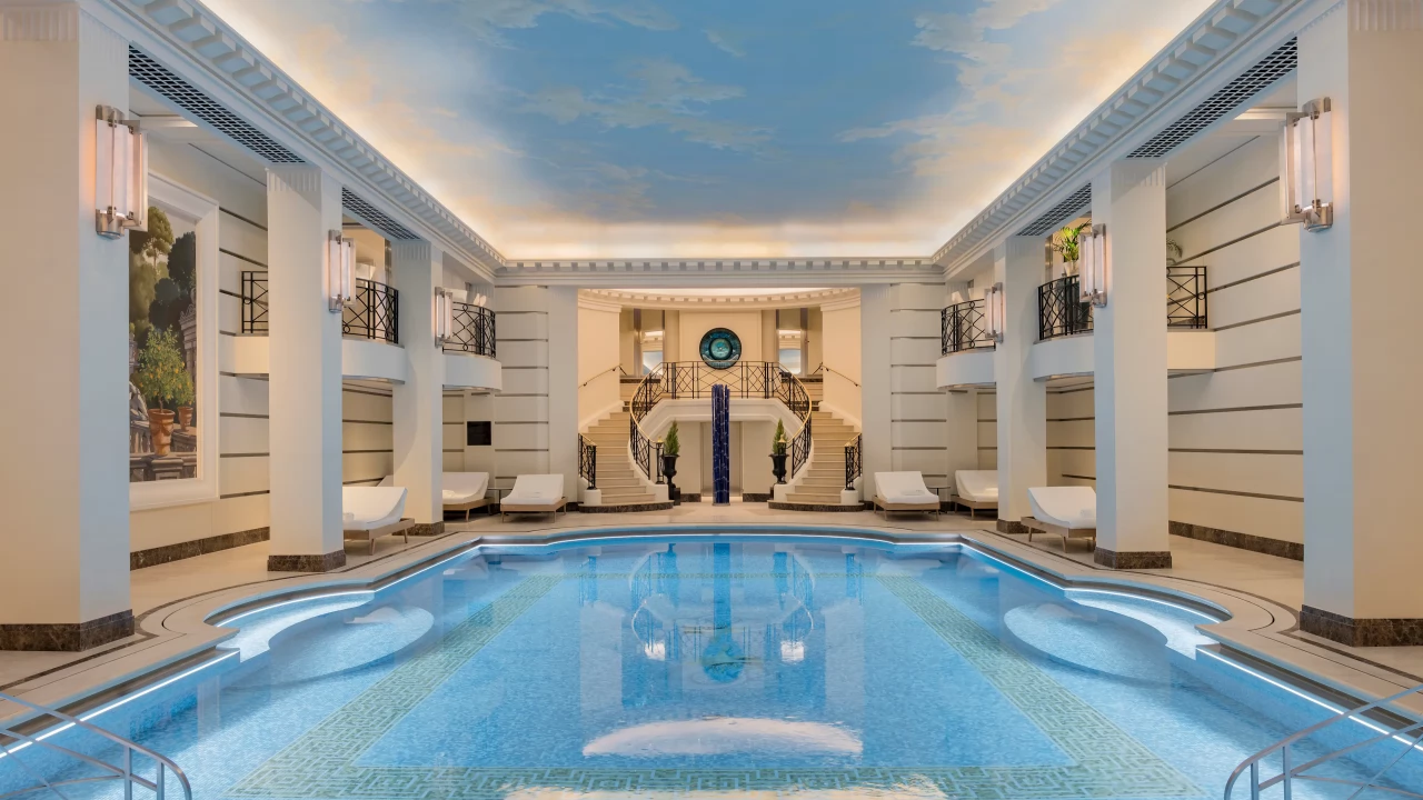 The stunning mosaic-tiled swimming pool at the Ritz Club & Spa, under a painted sky.