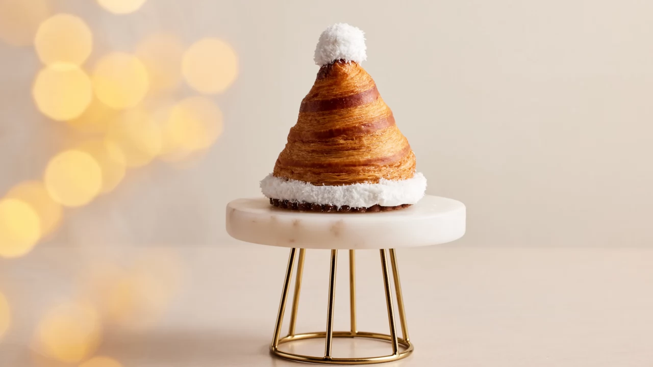 A festive Santa hat-shaped croissant from Sofitel Dubai The Palm, made with buttery, flaky layers and a white chocolate puffball.