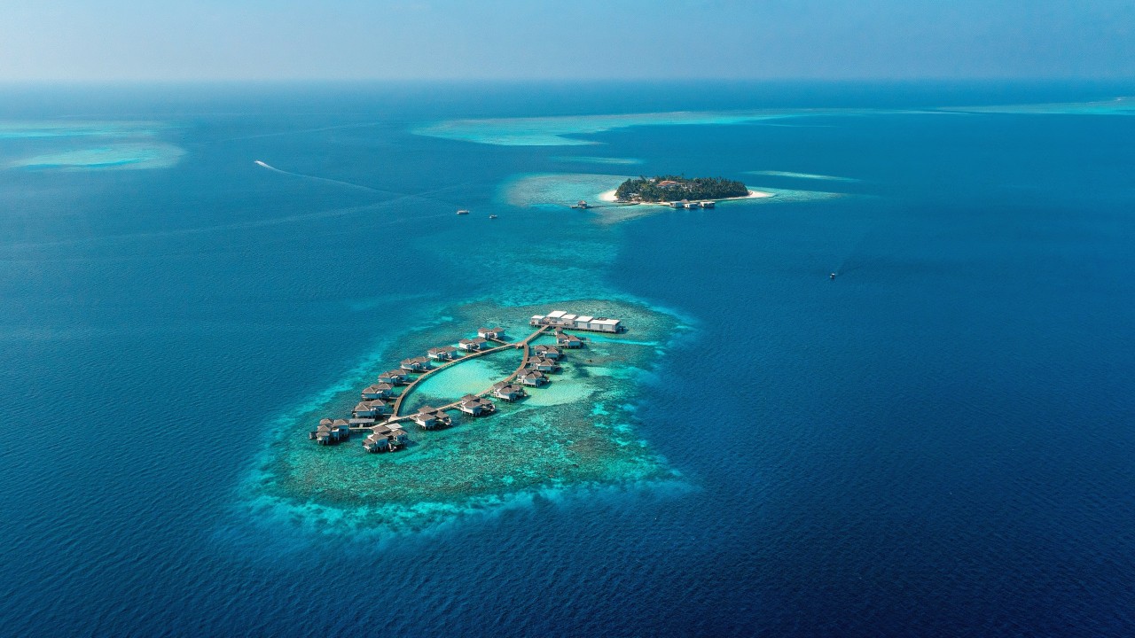A breathtaking aerial view of The Halcyon Private Isles Maldives, showcasing the resort's two pristine private islands surrounded by vibrant coral reefs.