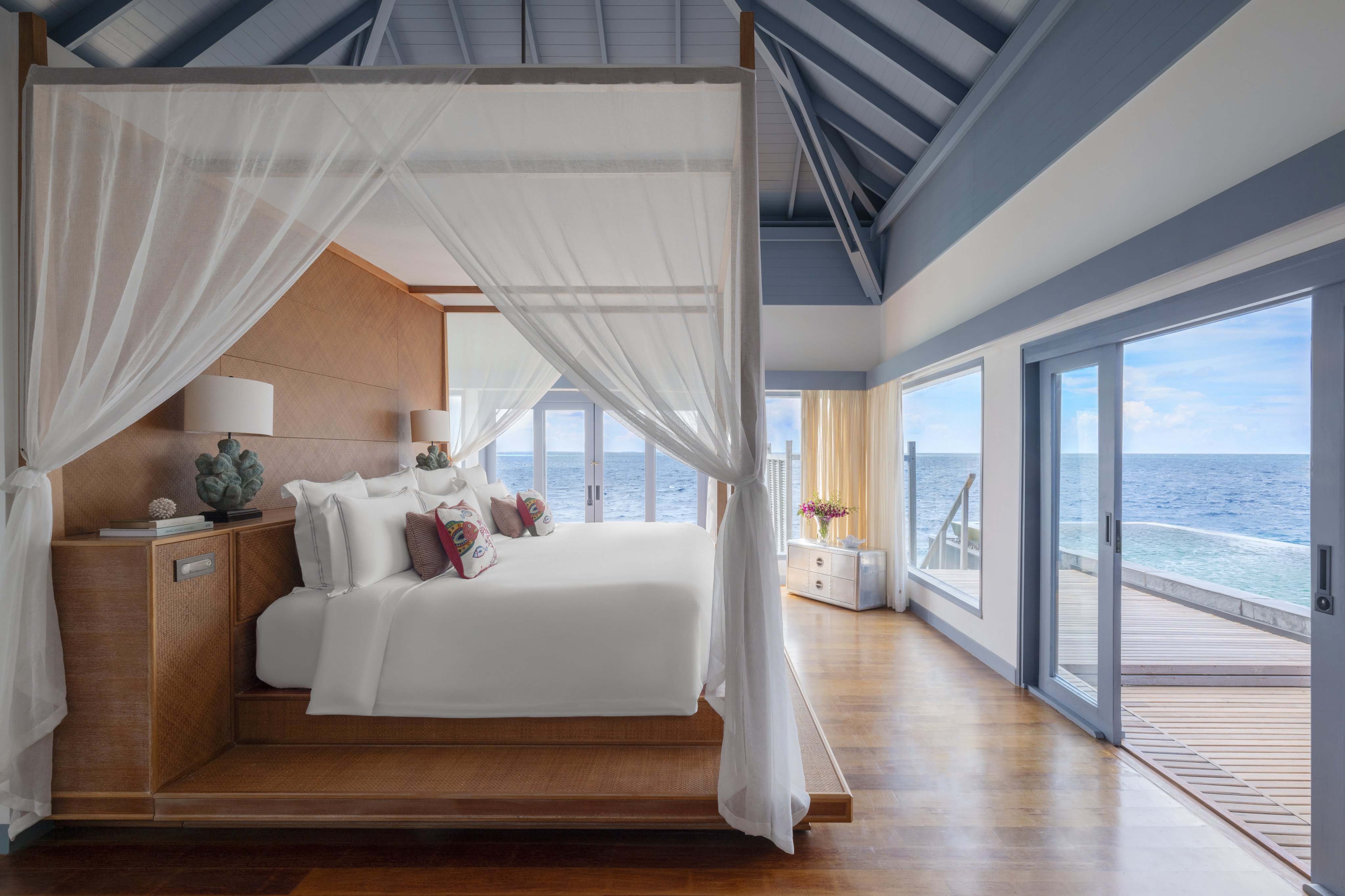 The master bedroom in a two-bedroom overwater retreat at The Halcyon Private Isles, showcasing elegant design and direct access to the private deck.