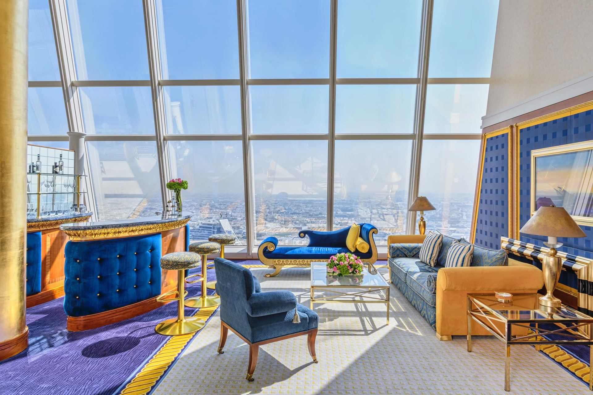 Expansive living area of a Duplex Club Suite at Burj Al Arab Jumeirah with gold-leaf pillars and floor-to-ceiling windows overlooking the Arabian Gulf.